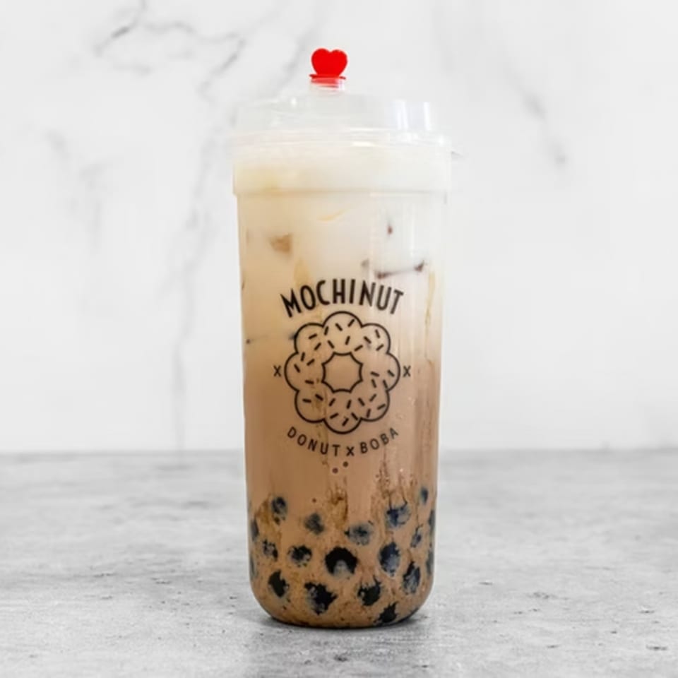 Mochinut boba tea with a red heart stopper on a white marble background.