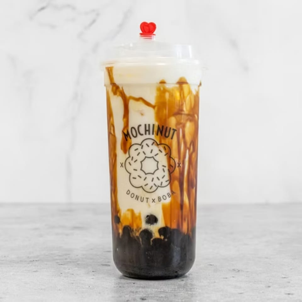 Mochinut boba drink with brown sugar syrup streaks, creamy white liquid, and dark boba pearls.