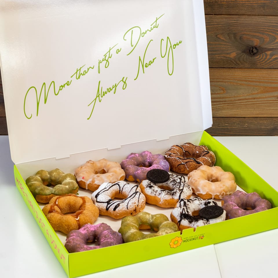 An open MochiNut box filled with a dozen colorful, uniquely shaped mochi donuts.