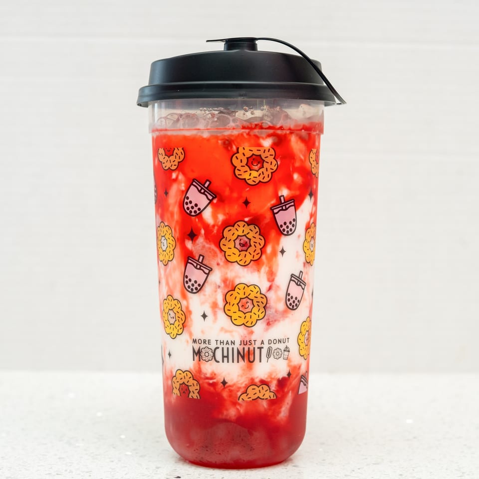A MochiNut strawberry milk tea with a black lid, featuring donut and boba cup illustrations.