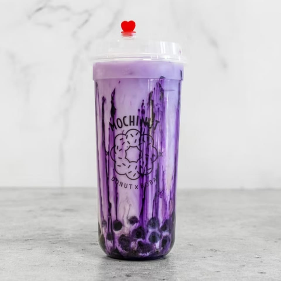 Mochinut taro boba tea with dark purple streaks and tapioca pearls, topped with a red heart.