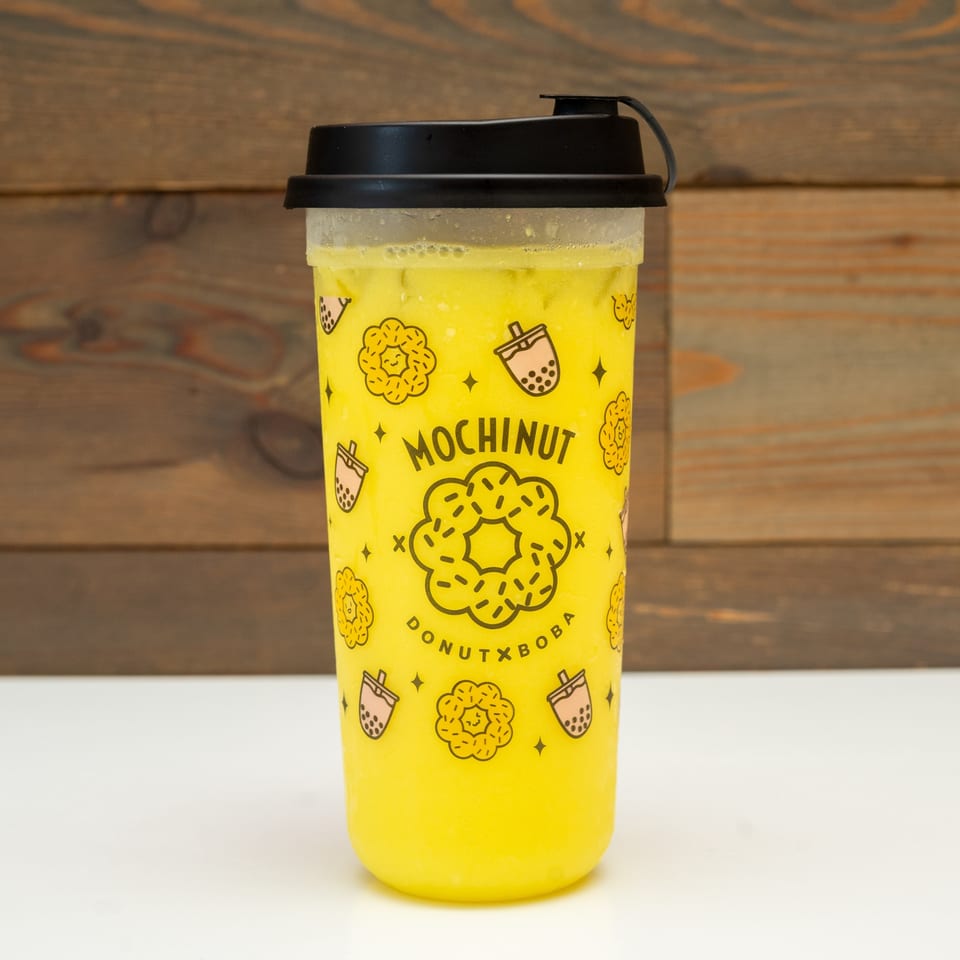 A MochiNut brand cup filled with a yellow drink, featuring donut and boba illustrations.