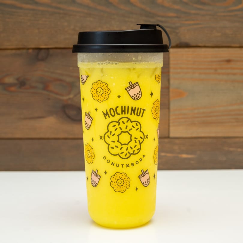 A MochiNut brand cup filled with a yellow drink, featuring donut and boba illustrations.