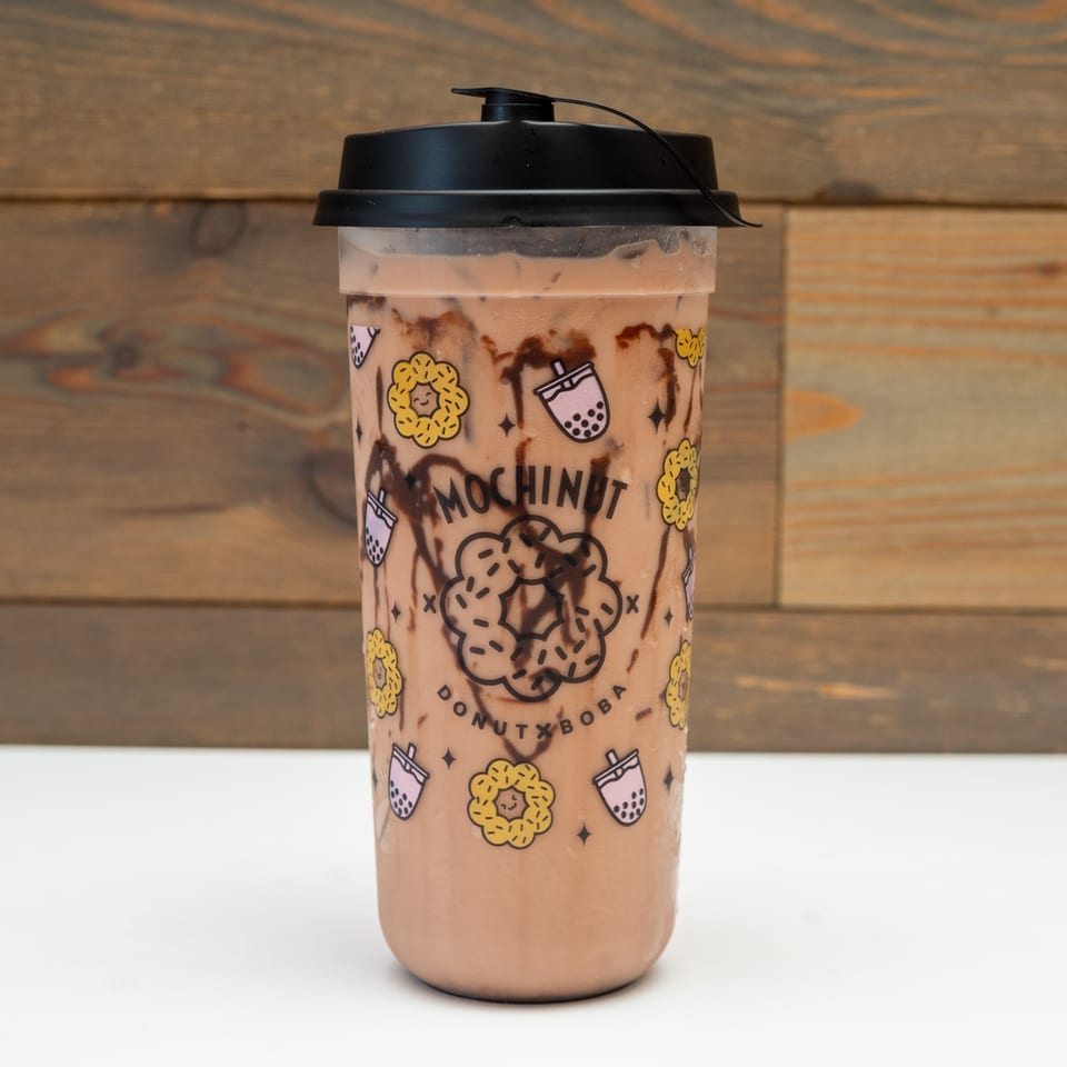 A MochiNut Donut x Boba branded cup with chocolate drizzle and a brown beverage.